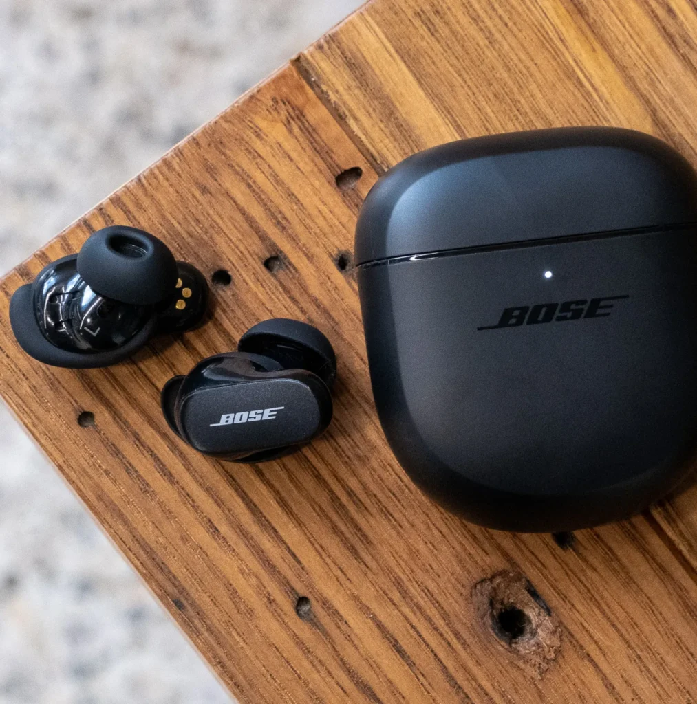 Bose QuietComfort Ultra 2nd Gen Premium Earbuds with case on wooden table as the best noise cancelling earbuds of 2026