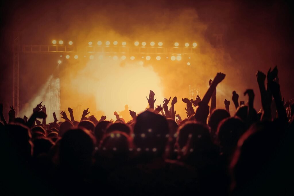 Live concert crowd with bright stage lights, representing Auracast earbuds, broadcast audio, shared listening, and wireless audio streaming at public events.
