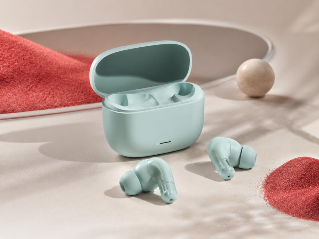 Mint green Redmi earbuds with open charging case on a soft beige surface with red textured accents.